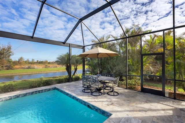 view of swimming pool featuring glass enclosure, a patio area, and a water view