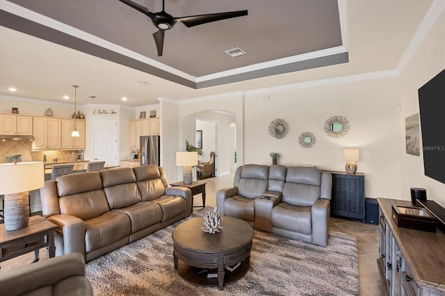 tiled living room with a tray ceiling, ceiling fan, and ornamental molding