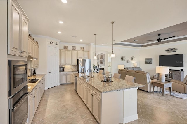 kitchen with sink, an island with sink, pendant lighting, appliances with stainless steel finishes, and ornamental molding