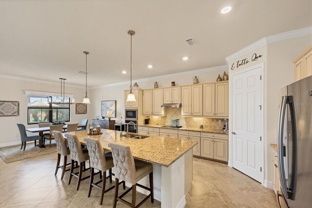 kitchen with a kitchen island with sink, sink, hanging light fixtures, ornamental molding, and stainless steel appliances