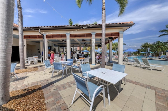 view of patio / terrace featuring ceiling fan, a water view, and a pool