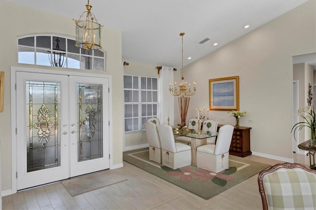 dining space featuring french doors, high vaulted ceiling, and an inviting chandelier