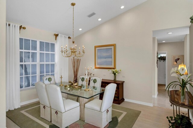 dining area with a chandelier, light wood-type flooring, and high vaulted ceiling