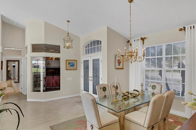 dining area with an inviting chandelier, light wood-type flooring, high vaulted ceiling, and french doors