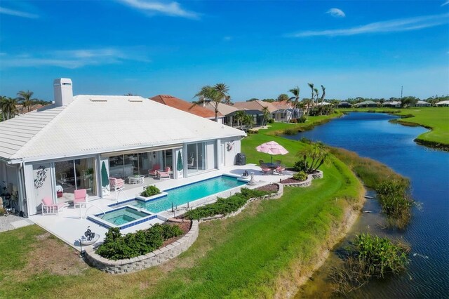 rear view of house with a swimming pool with hot tub, a water view, a yard, and a patio