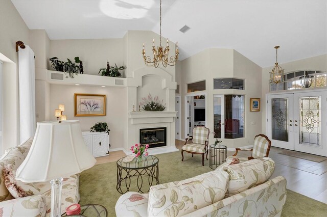 living room with french doors, hardwood / wood-style flooring, high vaulted ceiling, and a notable chandelier