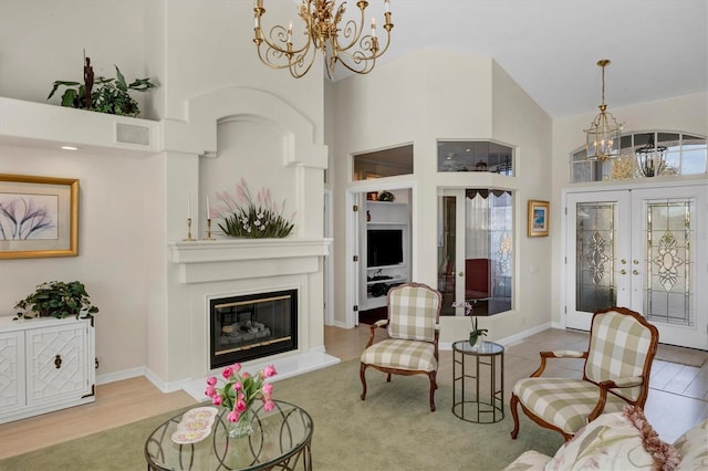 living room with french doors, light wood-type flooring, high vaulted ceiling, and a notable chandelier