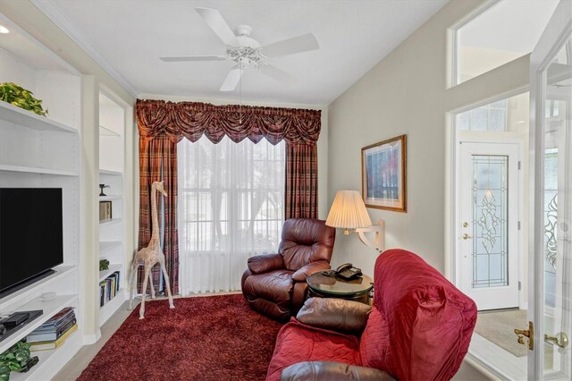 living room featuring carpet flooring, ceiling fan, built in features, and a healthy amount of sunlight