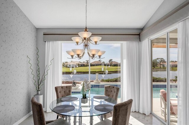 dining room featuring vaulted ceiling, a water view, an inviting chandelier, and a wealth of natural light