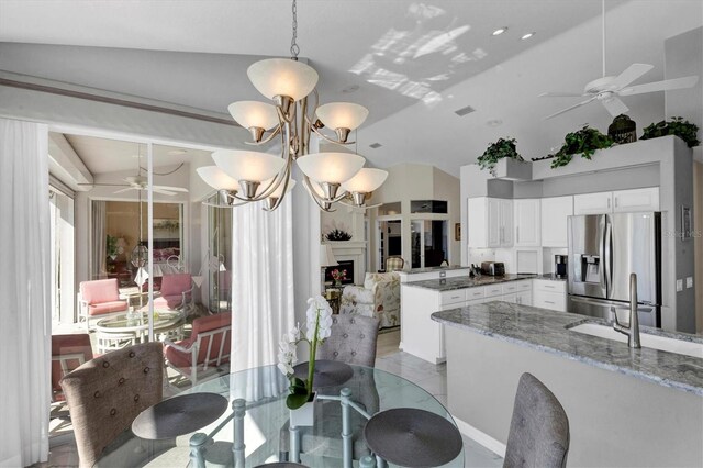 dining area with ceiling fan with notable chandelier, lofted ceiling, and sink