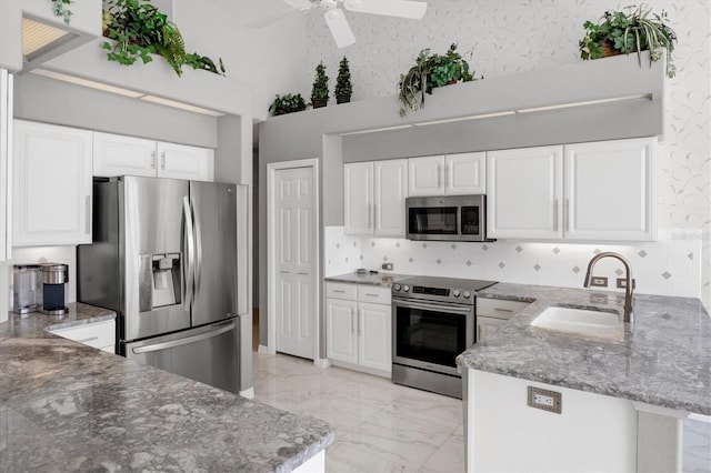 kitchen featuring white cabinets, sink, stone countertops, kitchen peninsula, and stainless steel appliances