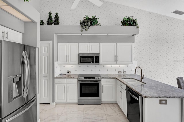 kitchen with stone counters, sink, kitchen peninsula, appliances with stainless steel finishes, and white cabinetry