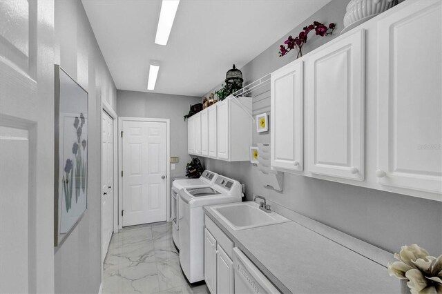 laundry area with cabinets, washer and clothes dryer, and sink