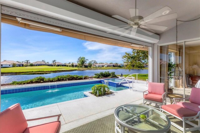 view of swimming pool featuring ceiling fan, pool water feature, a patio area, an in ground hot tub, and a water view