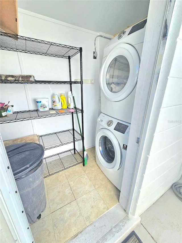 laundry room featuring stacked washing maching and dryer and light tile patterned floors