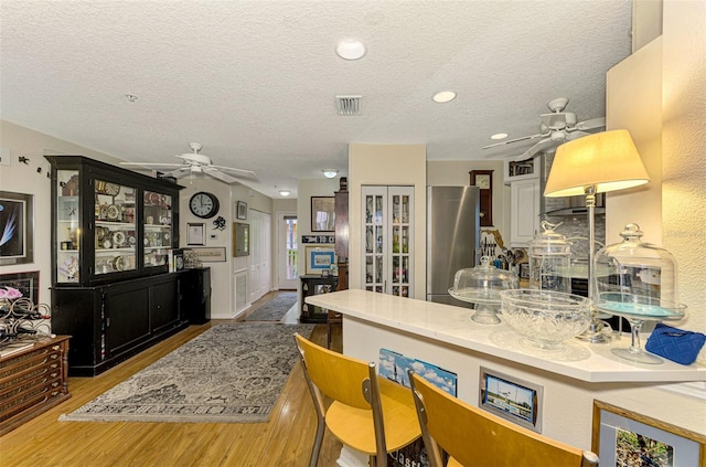 kitchen with stainless steel refrigerator, wood-type flooring, and a textured ceiling