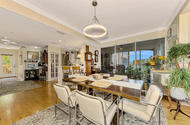 dining area with a textured ceiling, hardwood / wood-style flooring, ceiling fan, and crown molding