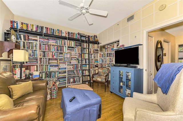 sitting room featuring ceiling fan, wood-type flooring, and a textured ceiling