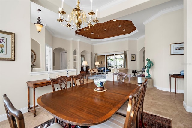 dining space featuring a raised ceiling, built in features, crown molding, and a chandelier