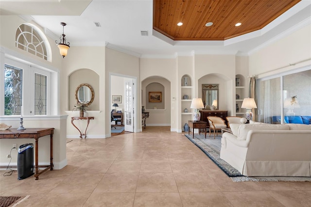 living room featuring wooden ceiling, built in shelves, ornamental molding, a tray ceiling, and a healthy amount of sunlight