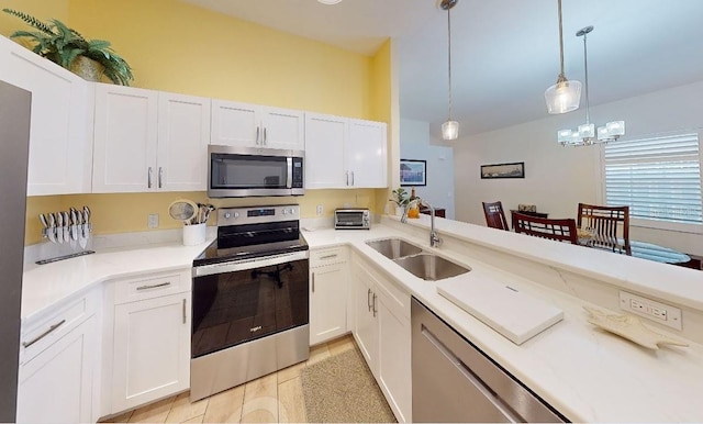 kitchen featuring an inviting chandelier, hanging light fixtures, sink, appliances with stainless steel finishes, and white cabinetry