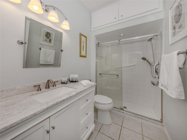 bathroom featuring tile patterned flooring, vanity, a shower with shower door, and toilet