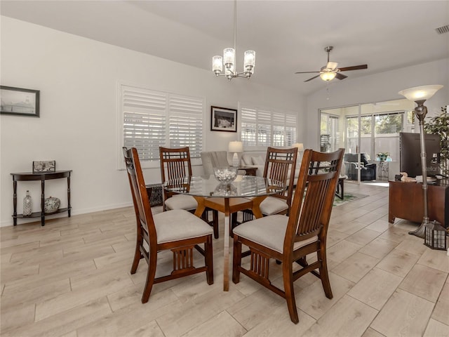 dining space with ceiling fan with notable chandelier, light hardwood / wood-style floors, and vaulted ceiling