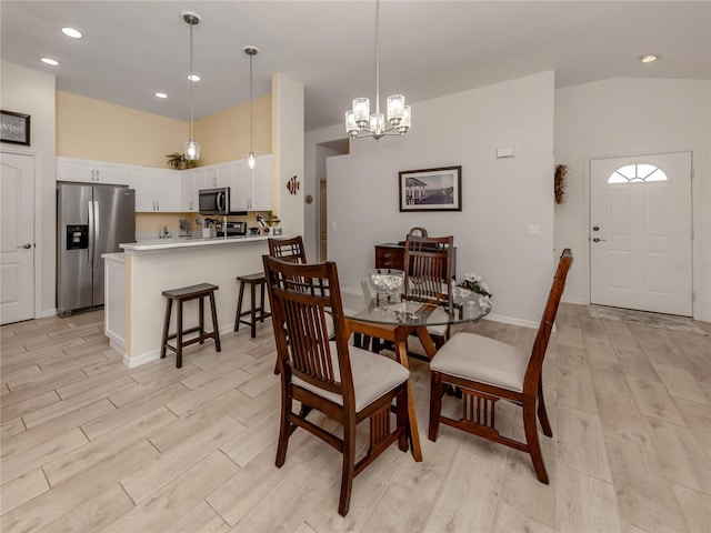 dining space featuring a chandelier, vaulted ceiling, and light hardwood / wood-style flooring