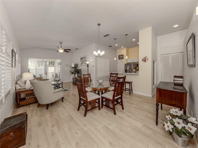 dining space featuring ceiling fan with notable chandelier, light hardwood / wood-style floors, and vaulted ceiling