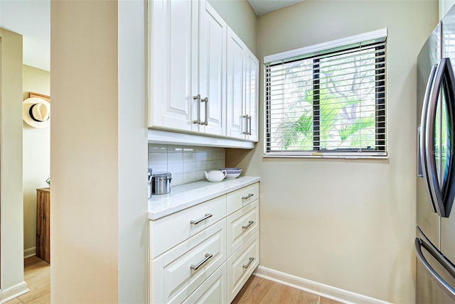 kitchen featuring decorative backsplash, stainless steel fridge, light hardwood / wood-style flooring, and white cabinetry