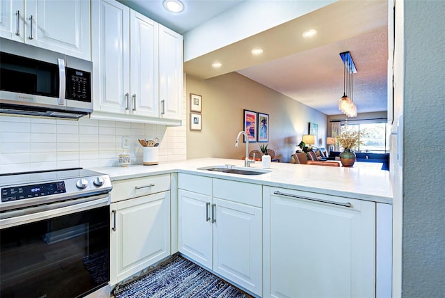 kitchen featuring sink, hanging light fixtures, kitchen peninsula, white cabinets, and appliances with stainless steel finishes