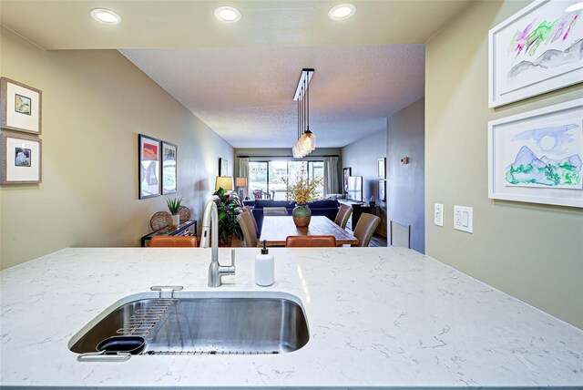 kitchen featuring light stone countertops, decorative light fixtures, and sink