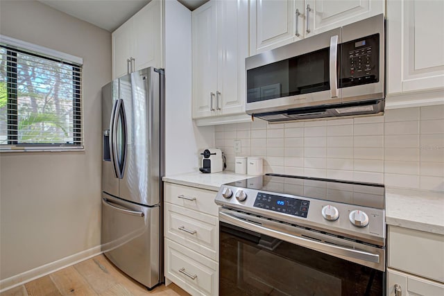 kitchen with stainless steel appliances, white cabinetry, tasteful backsplash, and light hardwood / wood-style flooring