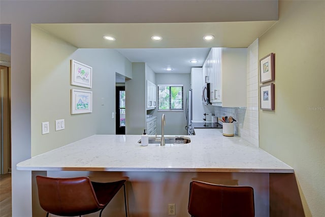 kitchen featuring sink, stainless steel appliances, a kitchen breakfast bar, kitchen peninsula, and decorative backsplash