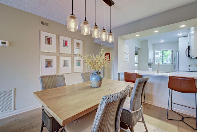 dining area with sink and light wood-type flooring