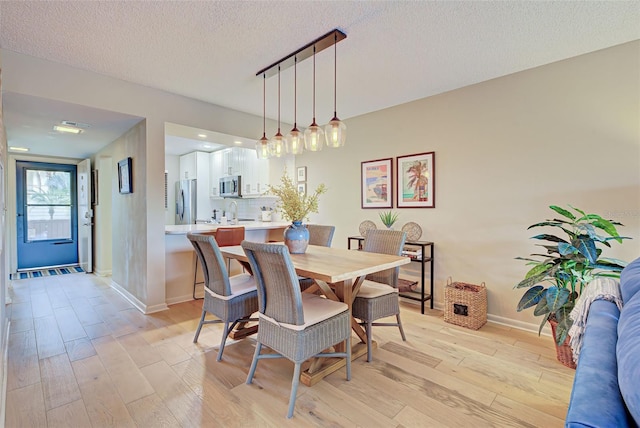 dining area with light hardwood / wood-style floors and a textured ceiling