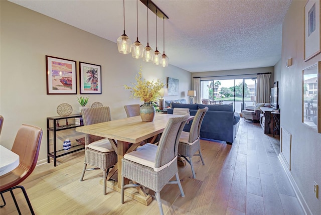 dining space with a textured ceiling and light hardwood / wood-style flooring