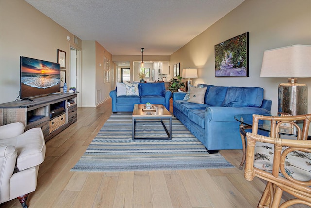 living room with a textured ceiling and light hardwood / wood-style flooring