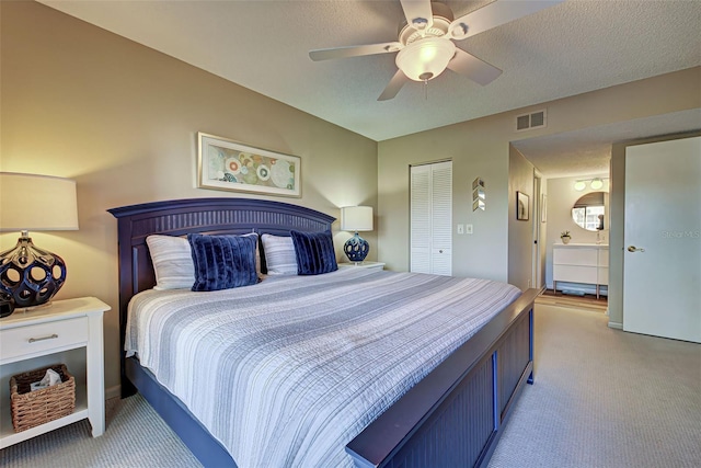 carpeted bedroom featuring ceiling fan, a closet, ensuite bathroom, and a textured ceiling