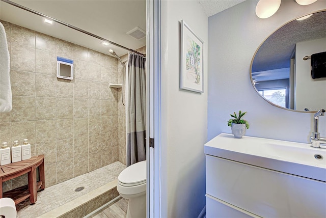 bathroom featuring walk in shower, a textured ceiling, toilet, vanity, and hardwood / wood-style flooring