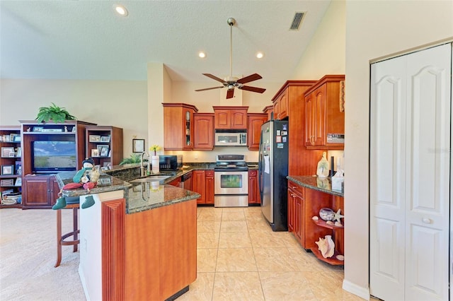 kitchen with ceiling fan, sink, stainless steel appliances, kitchen peninsula, and a breakfast bar