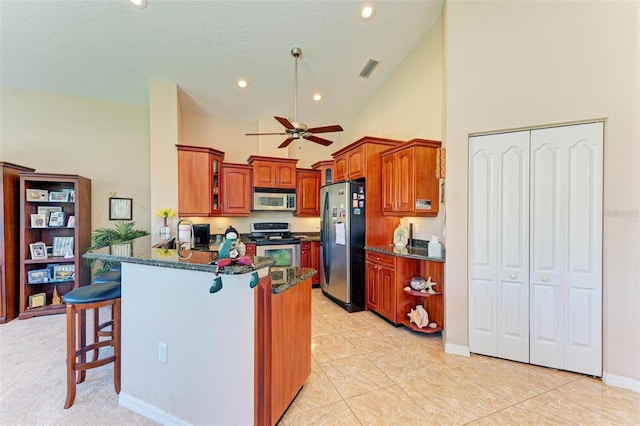 kitchen with ceiling fan, high vaulted ceiling, kitchen peninsula, a breakfast bar area, and appliances with stainless steel finishes