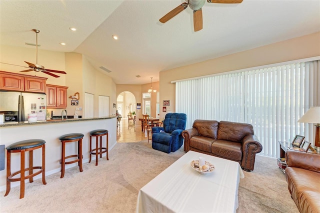 living room with light carpet, high vaulted ceiling, ceiling fan with notable chandelier, sink, and a textured ceiling