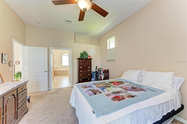 bedroom featuring light carpet, ensuite bath, and ceiling fan