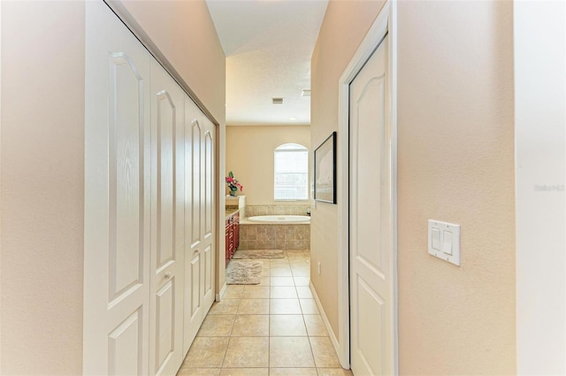 hall featuring light tile patterned floors and a textured ceiling