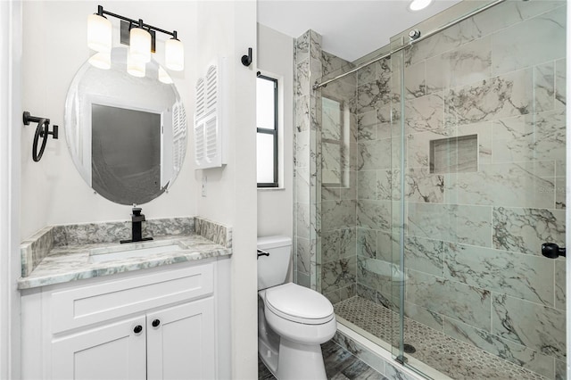 bathroom featuring vanity, a shower with shower door, and toilet