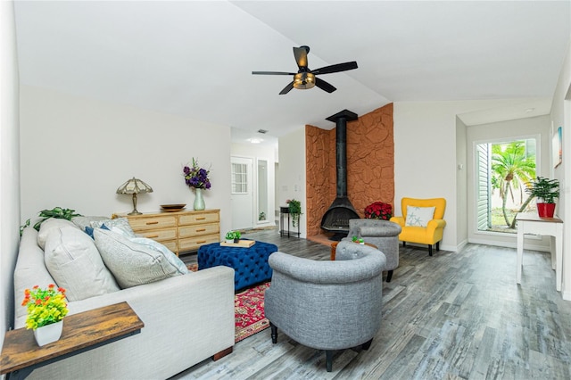 living room featuring hardwood / wood-style floors, vaulted ceiling, ceiling fan, and a wood stove