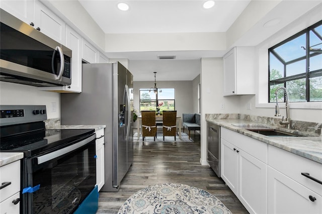 kitchen with appliances with stainless steel finishes, a wealth of natural light, sink, white cabinets, and light stone counters