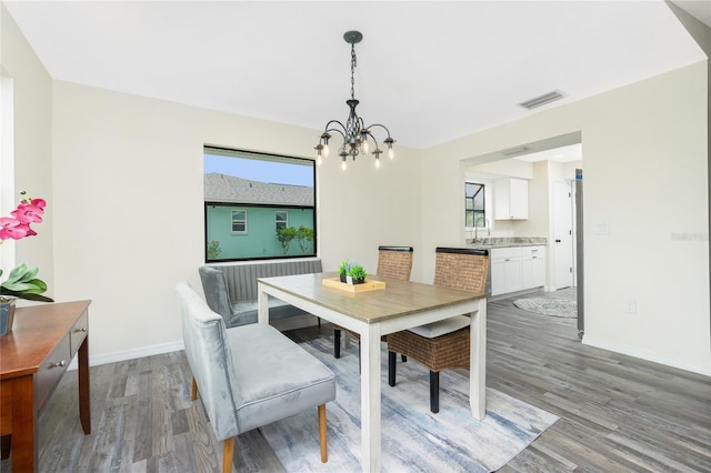 dining room featuring sink, hardwood / wood-style floors, and an inviting chandelier