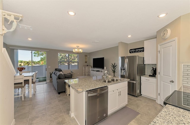 kitchen with a kitchen island with sink, sink, decorative backsplash, white cabinetry, and stainless steel appliances